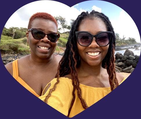 A mother and her daughter smiling outside.