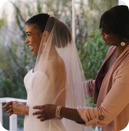 An older adult stands with a younger woman in a bridal gown